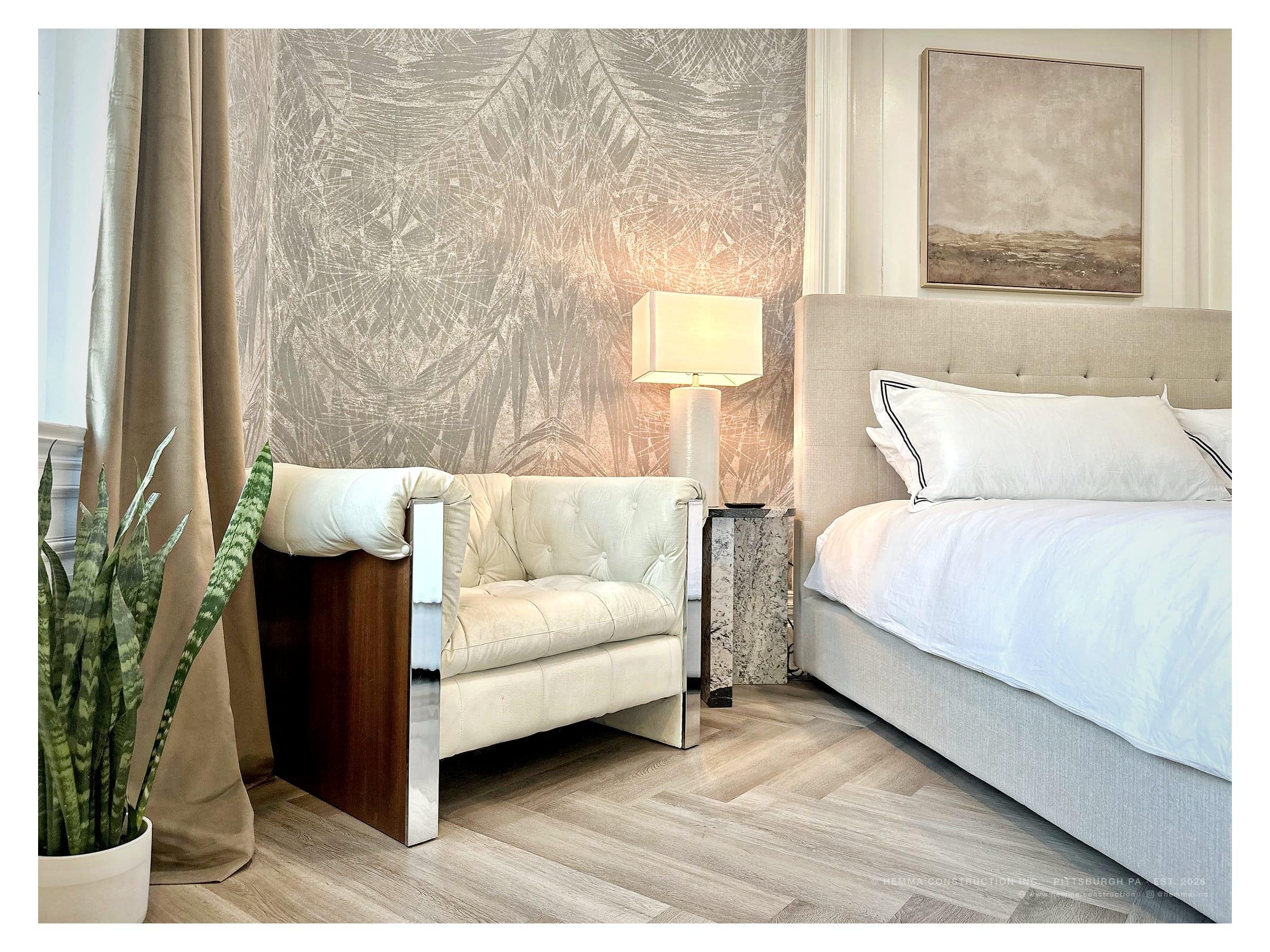 Primary bedroom with lounge chair, patterned wallpaper