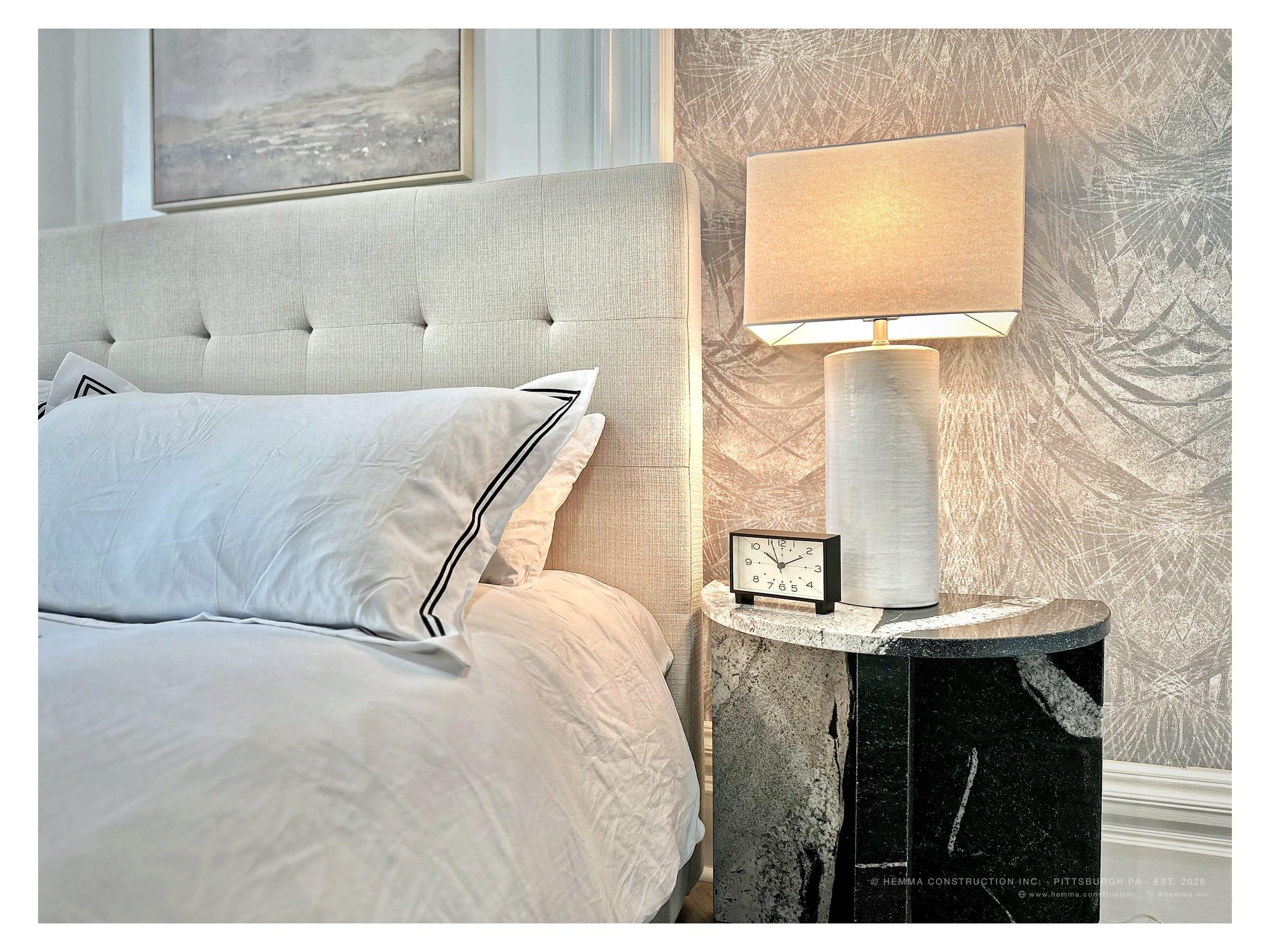 Bed with tufted headboard and lamp, patterned wallpaper