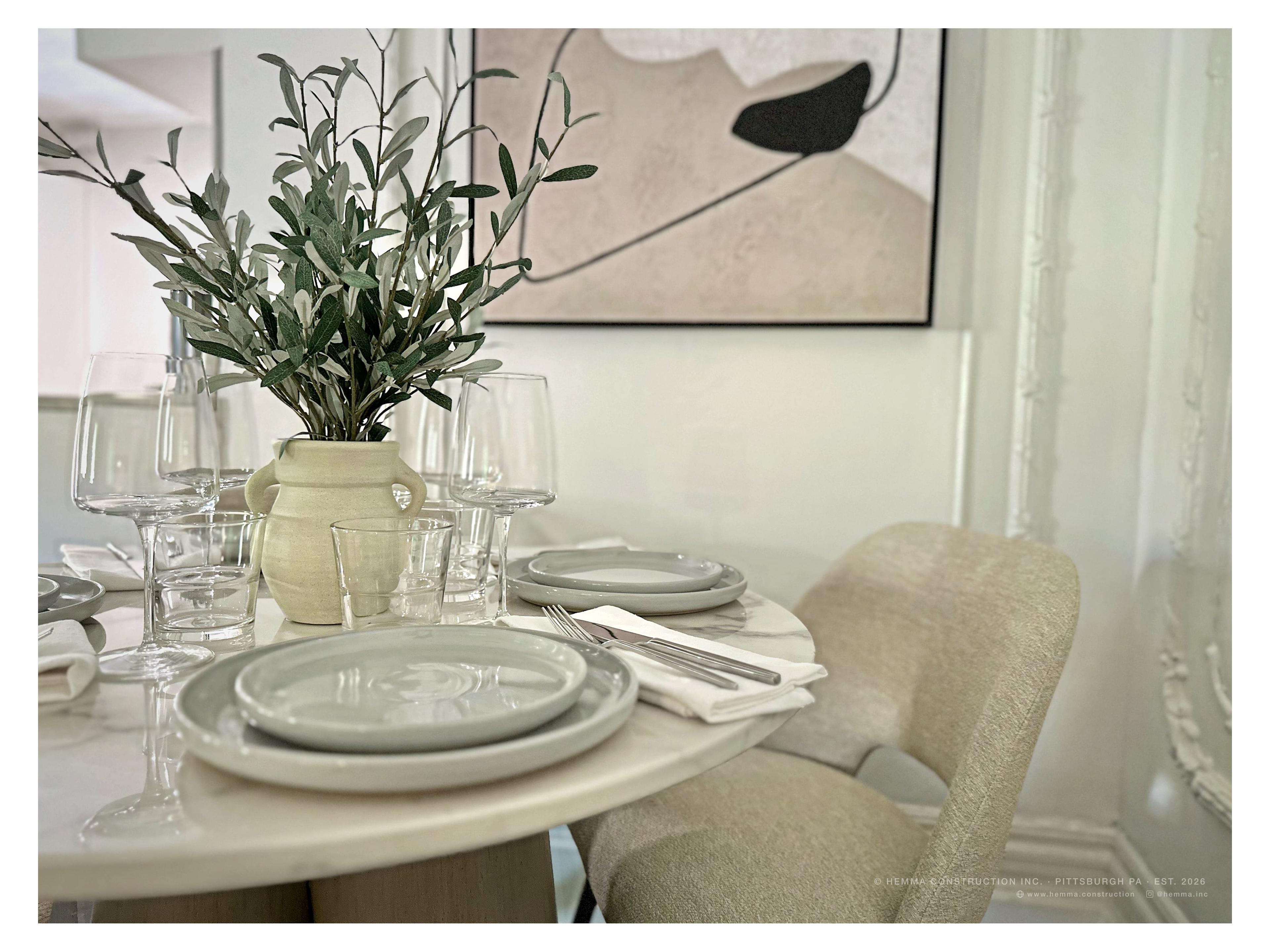Dining table close-up with olive branch arrangement and glassware