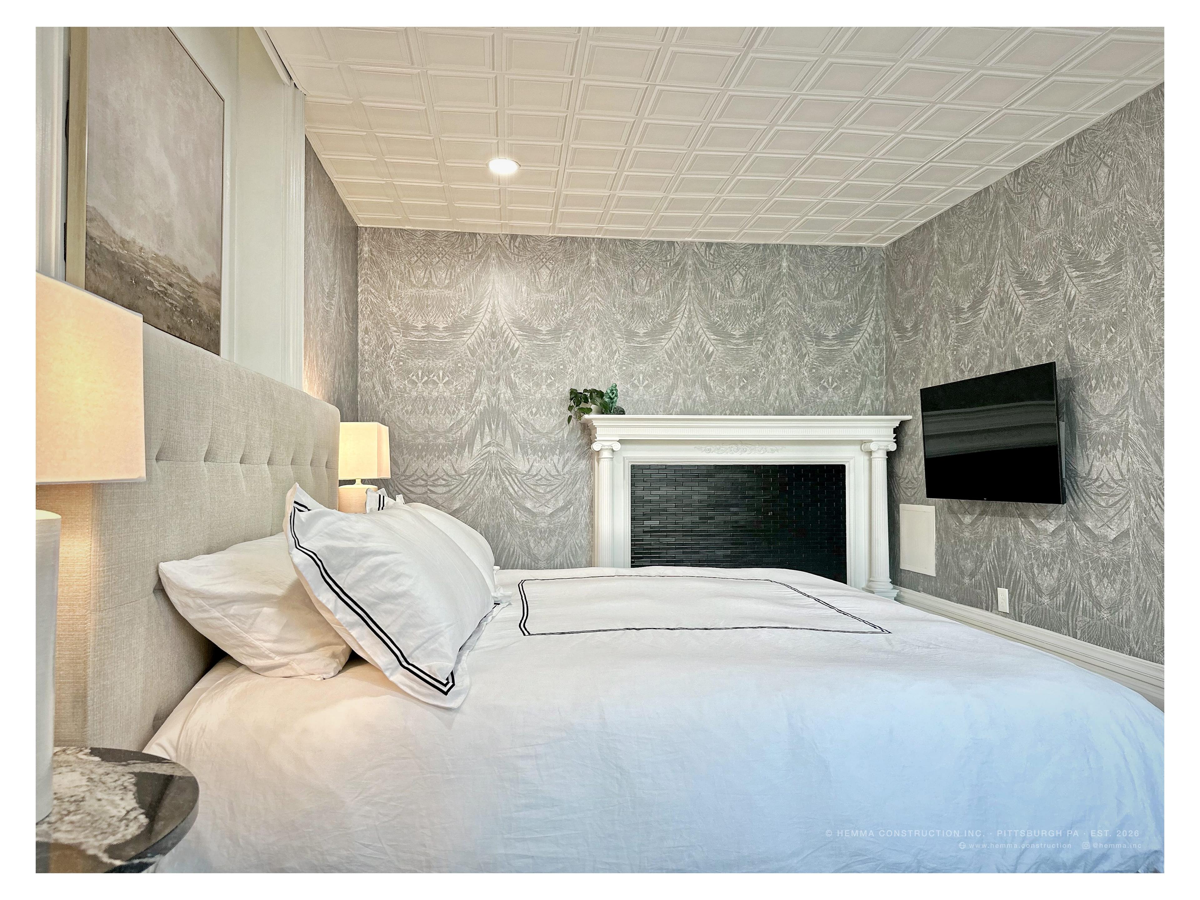 Bedroom with original fireplace, patterned wallpaper and tufted headboard