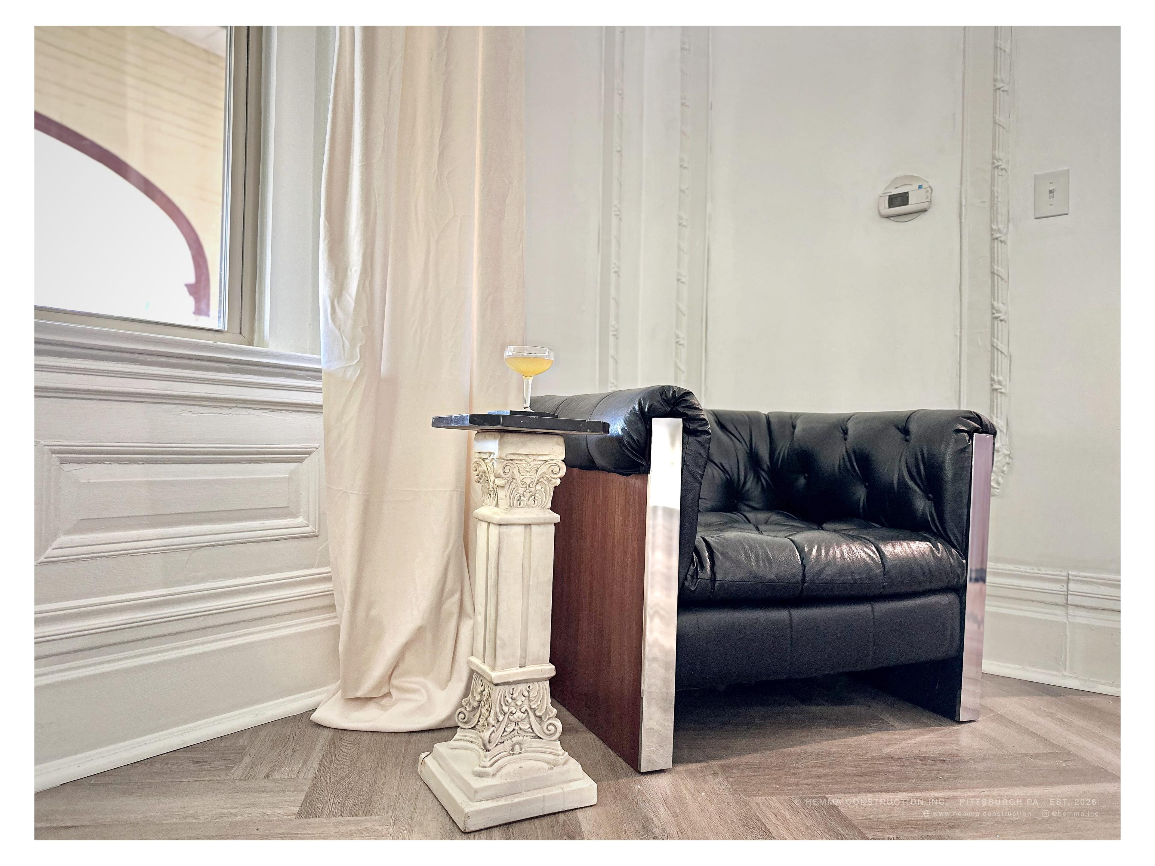 Black leather lounge chair in corner with pedestal lamp