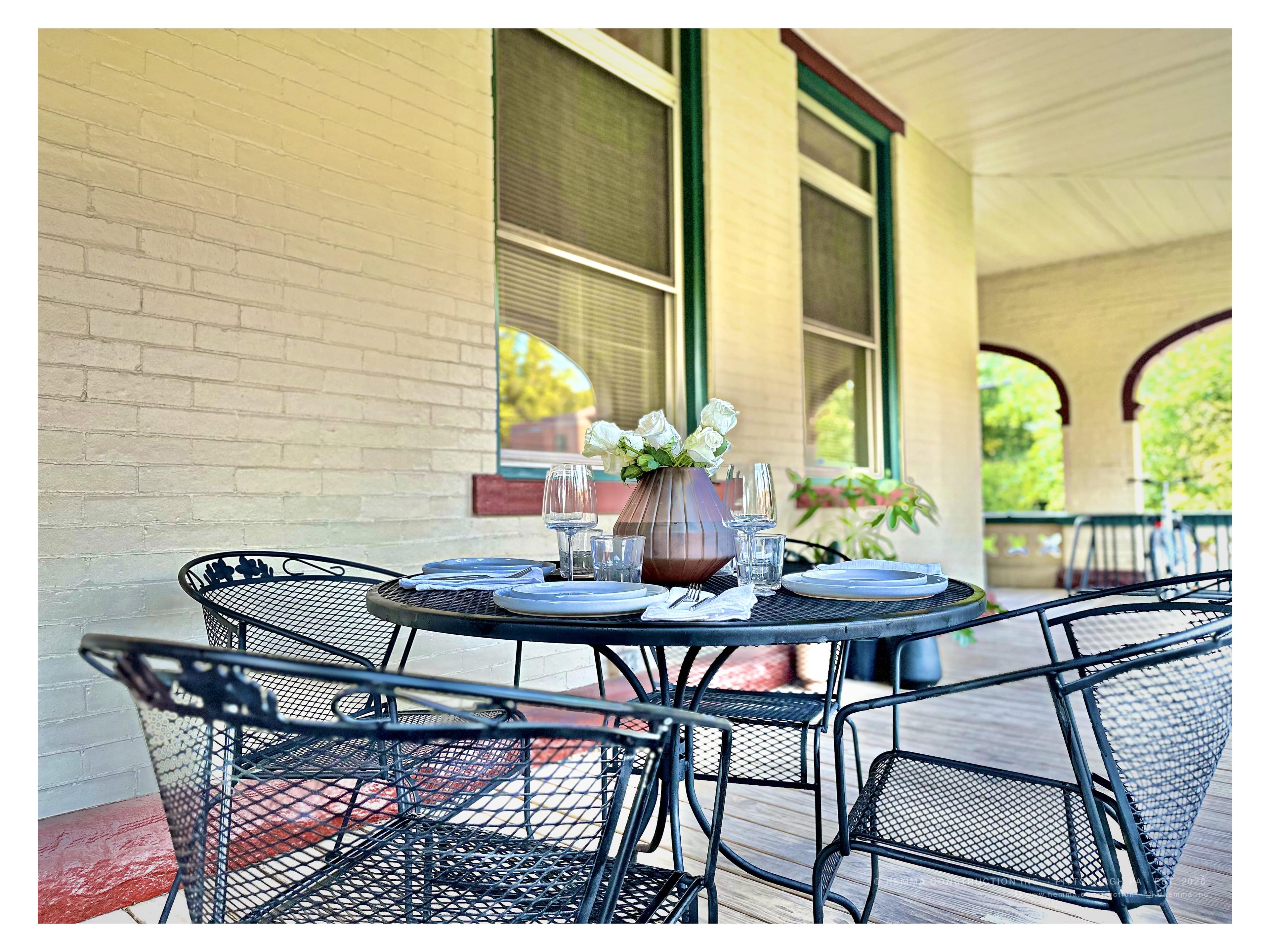 Front porch — wrought iron dining set with flower arrangement