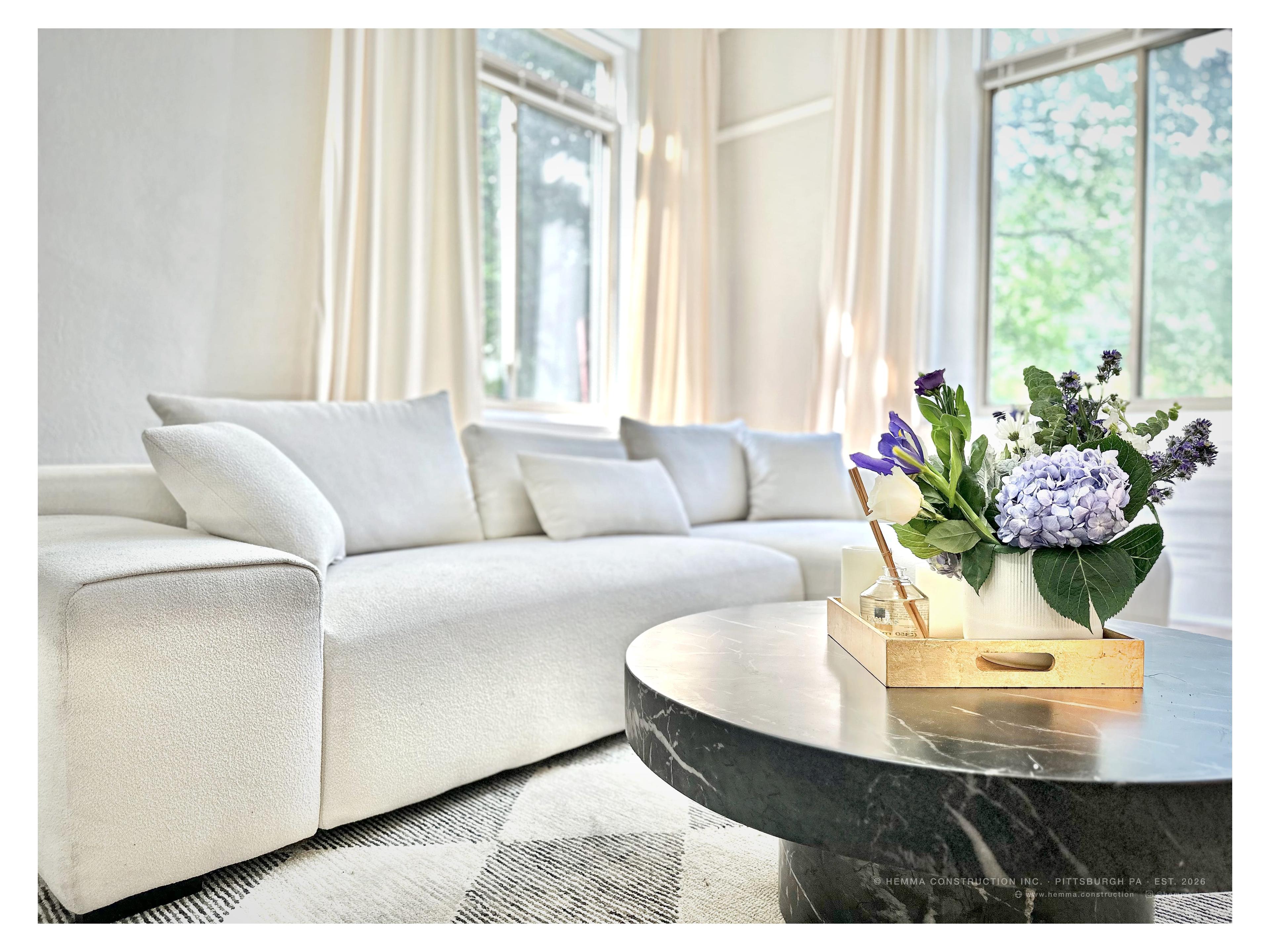 Living room — white sofa, marble coffee table, hydrangea arrangement, tall garden windows