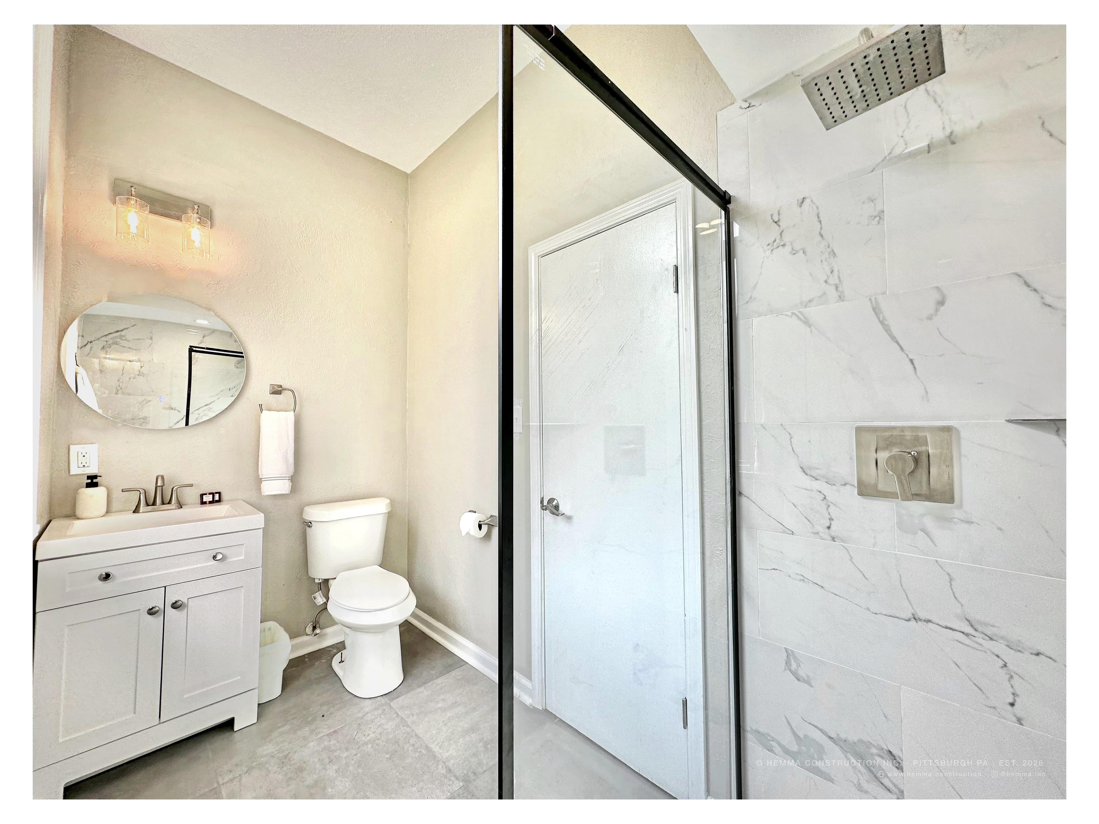 Bathroom — oval mirror, marble walk-in shower, white vanity