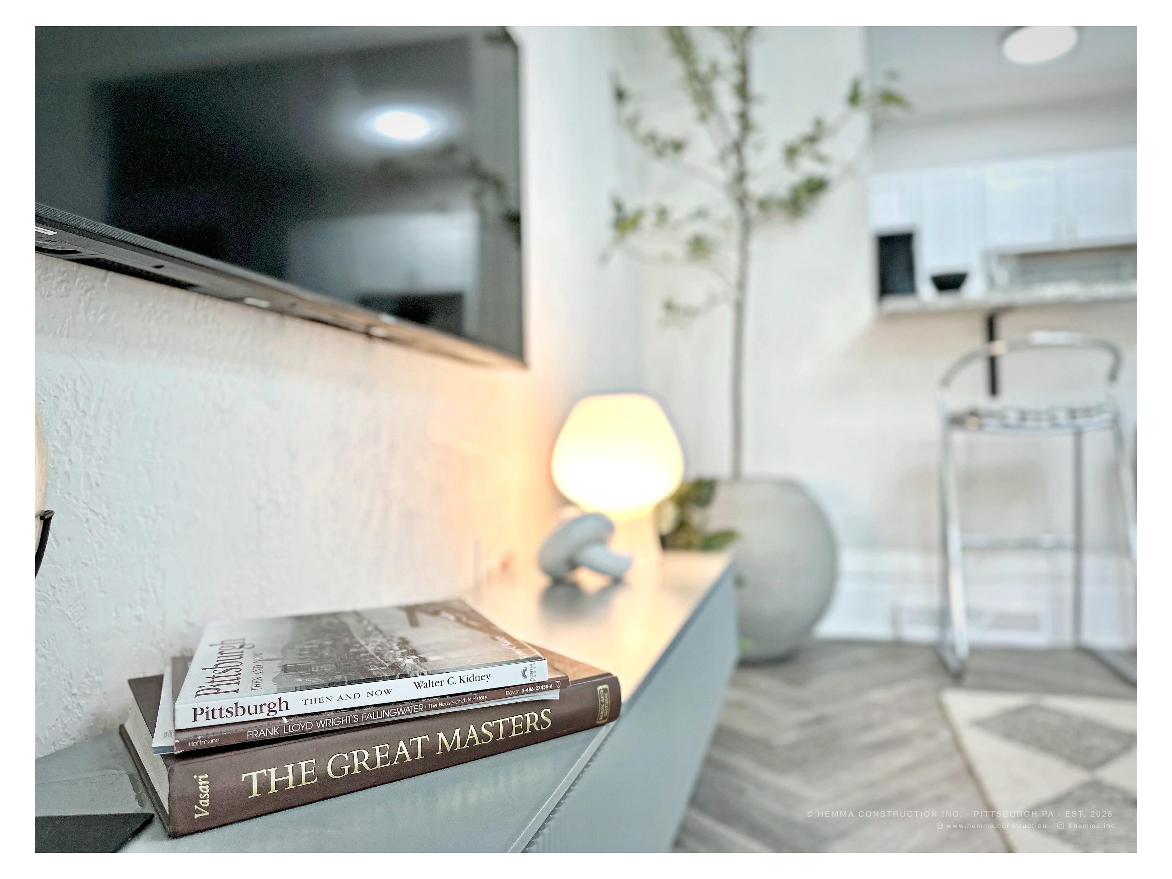 Console detail — Pittsburgh books, mushroom lamp, kitchen beyond