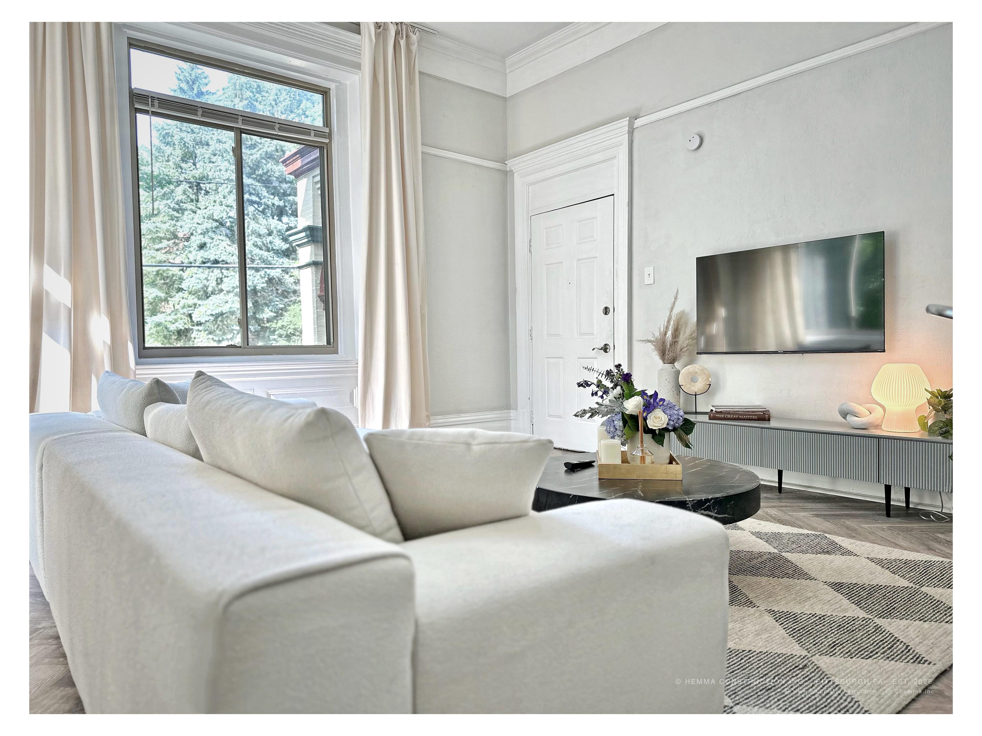 Living room — white sofa, dark marble coffee table, original crown molding, garden view