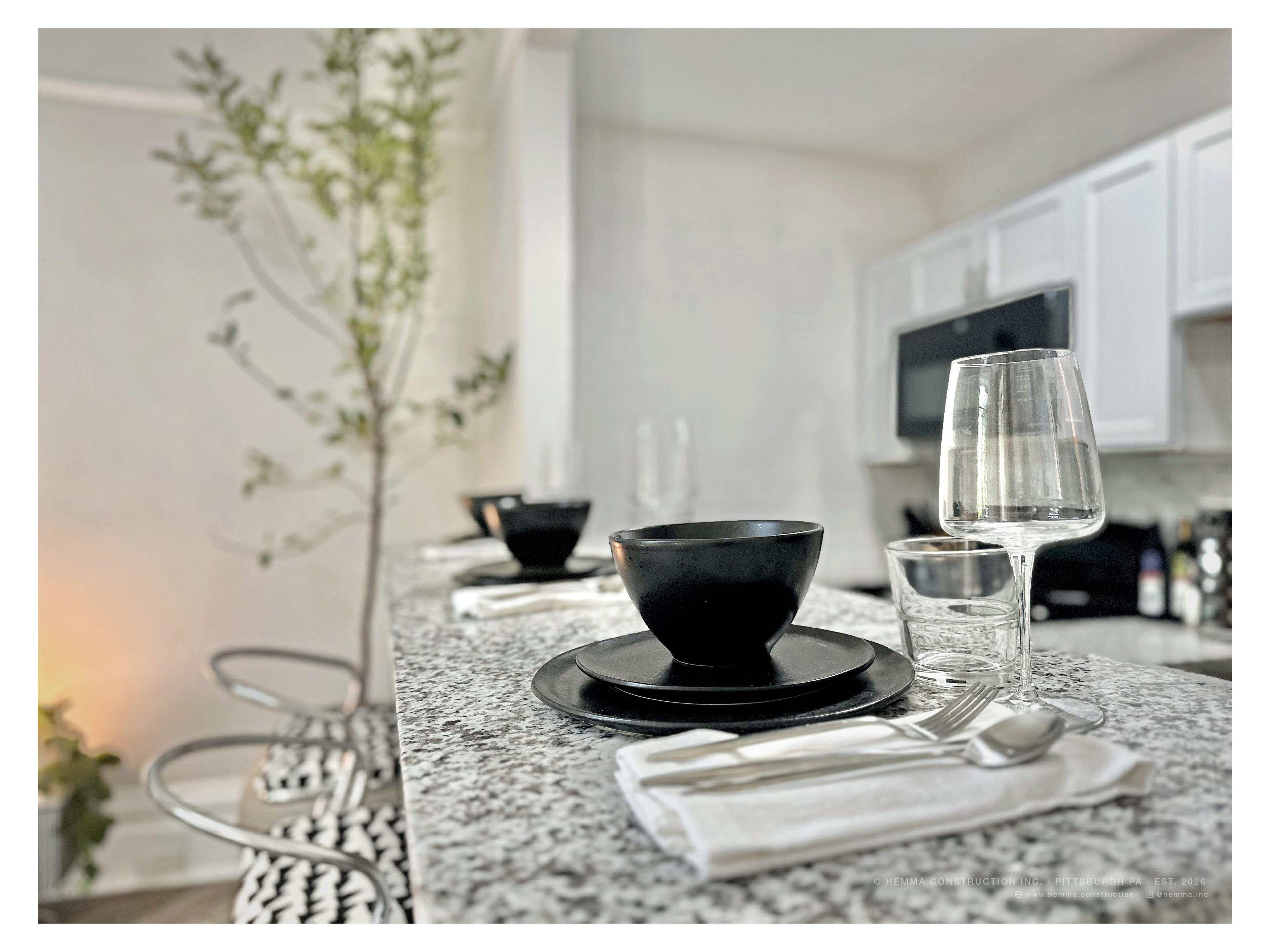 Kitchen counter — black place setting, wine glasses, granite surface