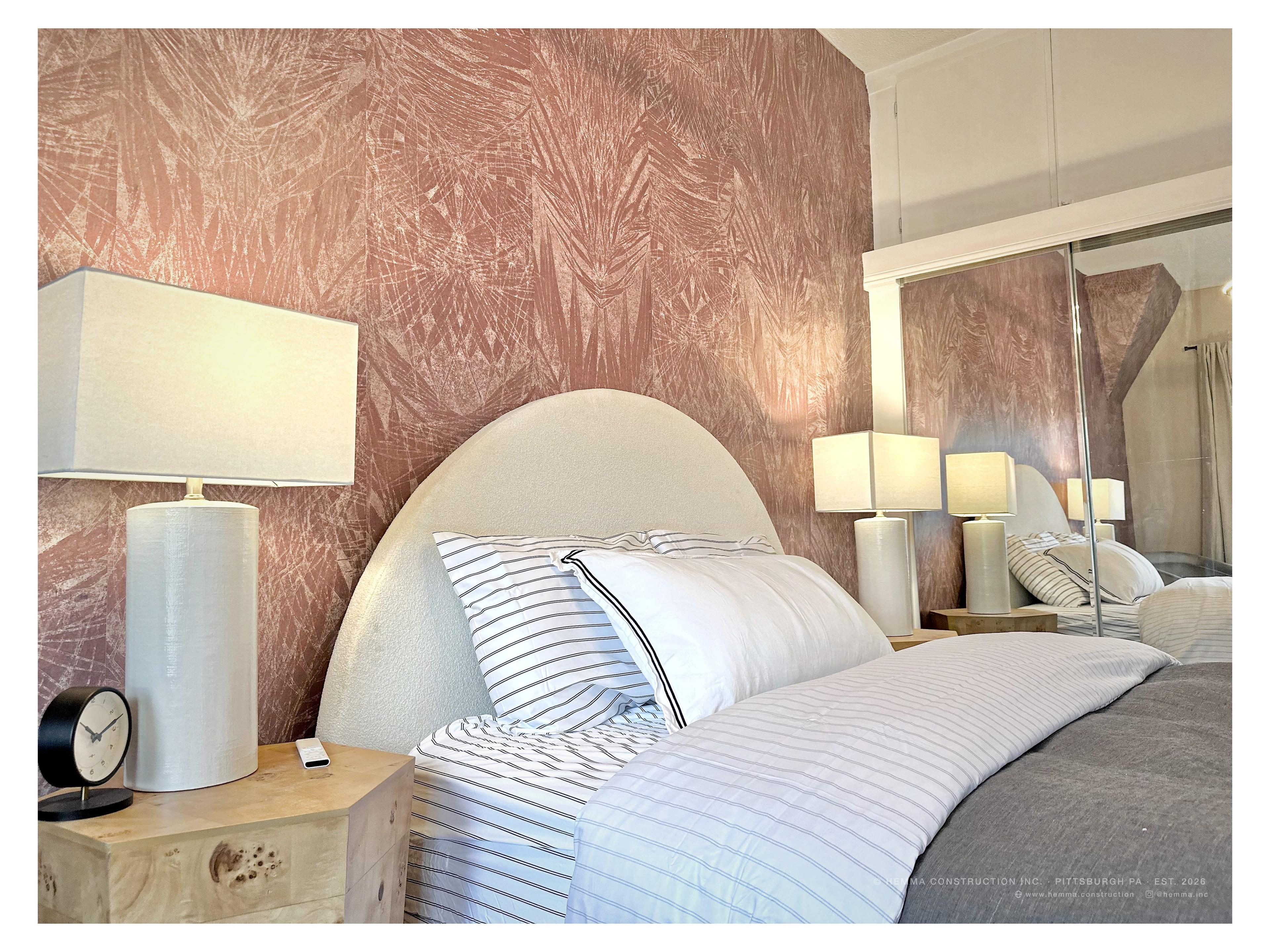 Bedroom — arched headboard, pink botanical wallpaper, striped hotel linen, paired lamps