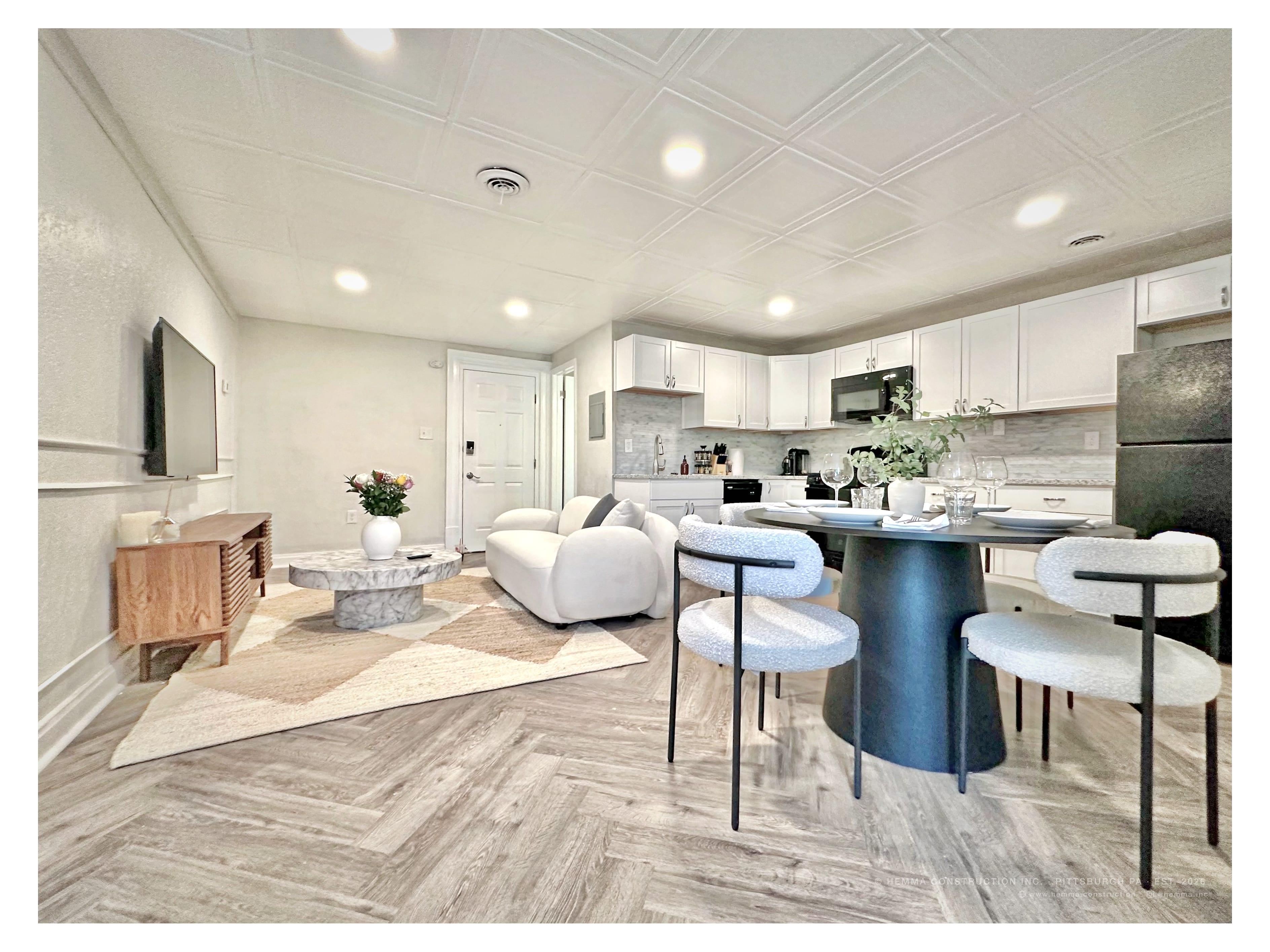 Living room full — white sofa, marble coffee table, dining area, kitchen, herringbone floor