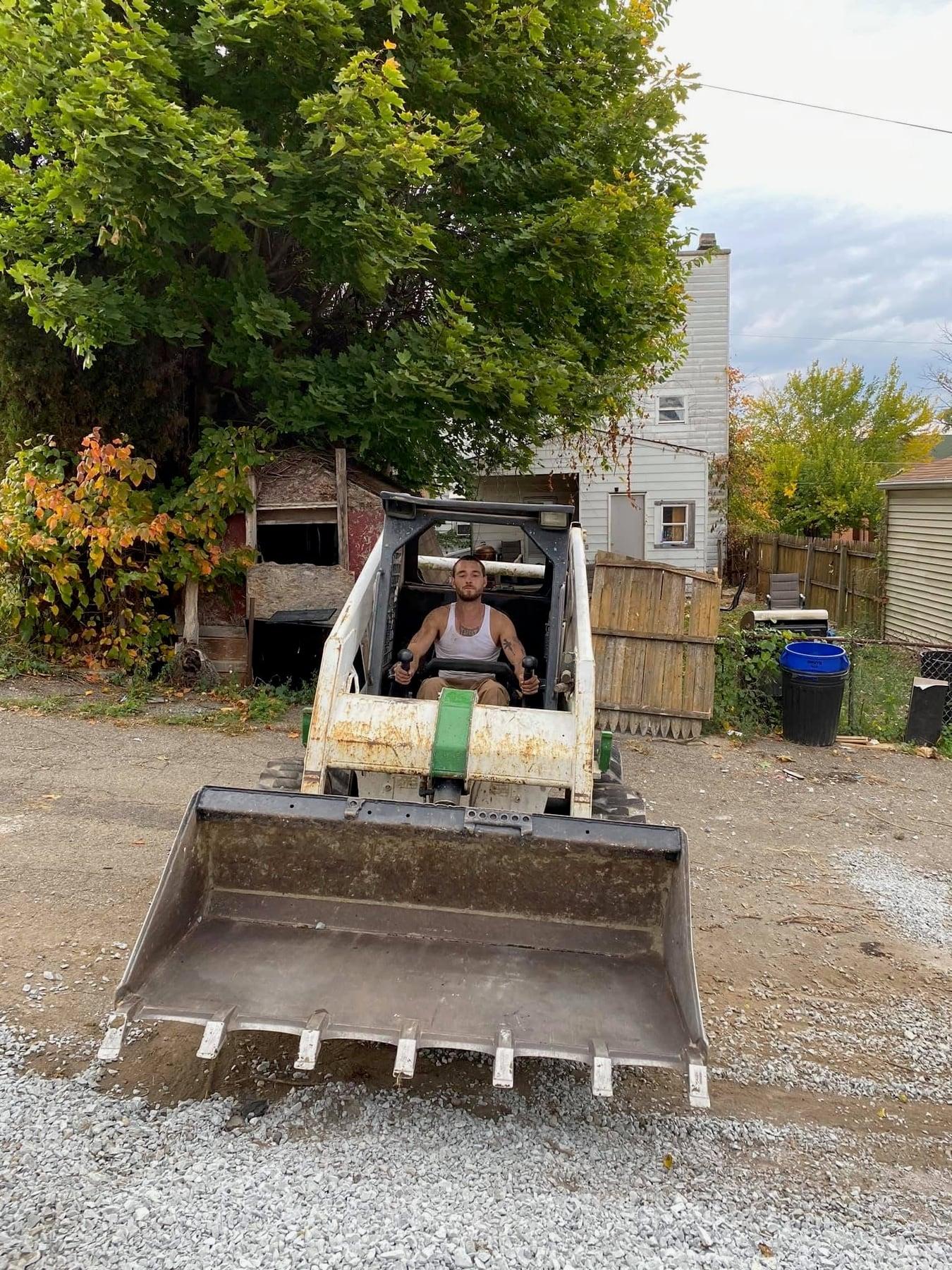 Matthew Bücher at the controls of a skid-steer on a Pittsburgh build site.